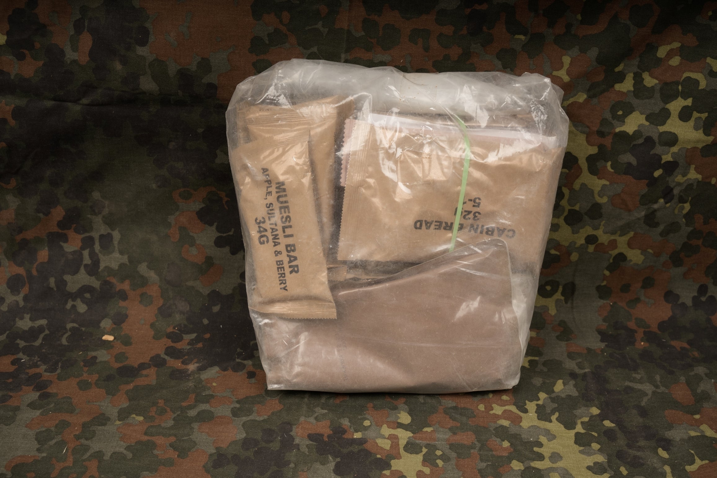 Frontalbild einer 24Stunden Neuseeland Ration, NZ-Ration vor einem Flecktarn Hintergrund